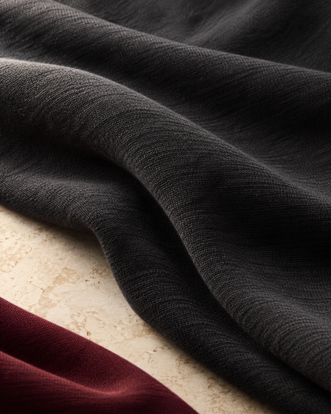 Charcoal fabric draped over ivory stone with a burgundy accent